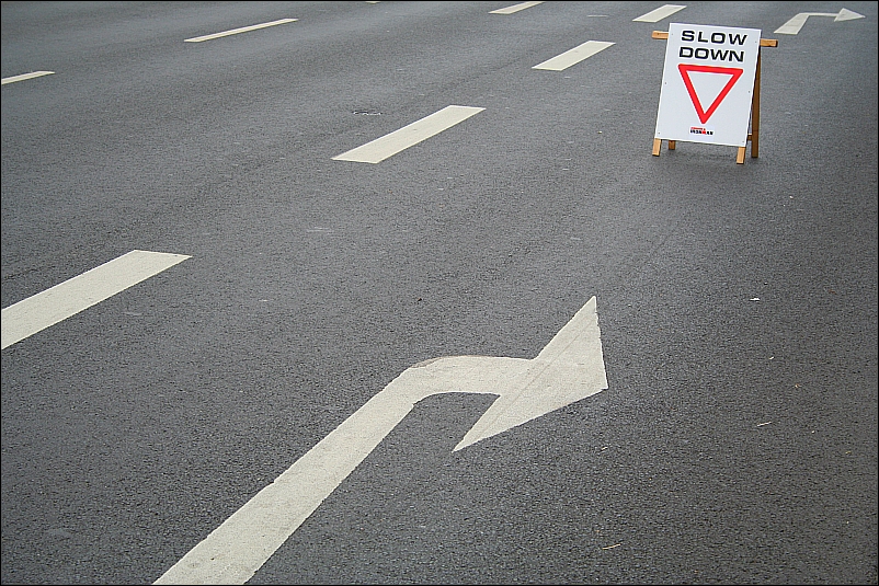 a road with a sign board showing 'Slow'